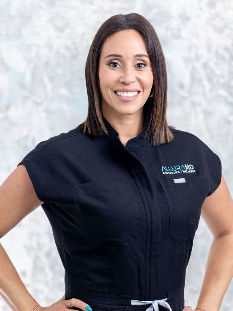alluramd founder and aesthetic nurse professional evelyn rodriquez standing in her uniform smiling broadly
