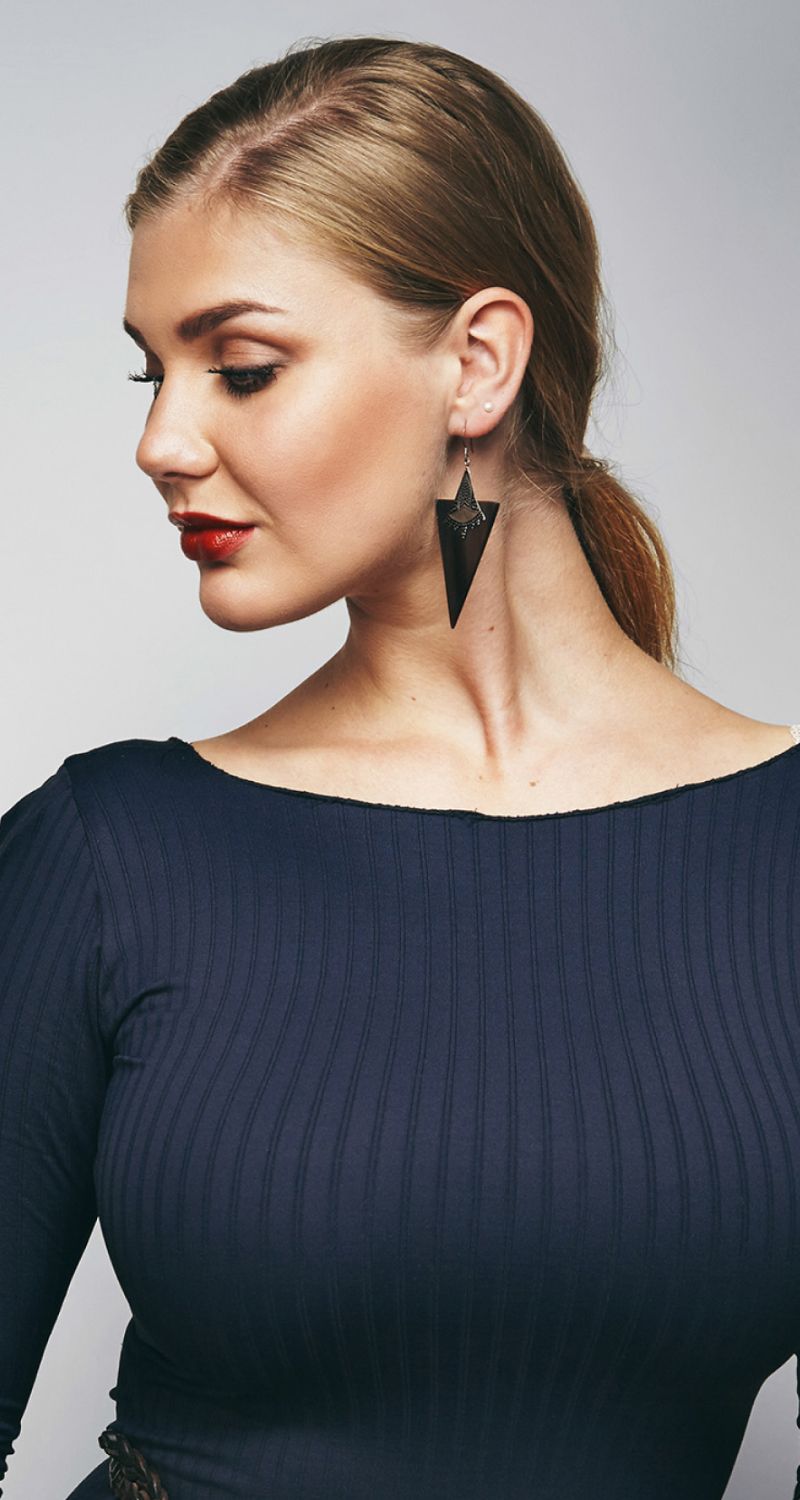 Woman in navy dress with stylish earrings.