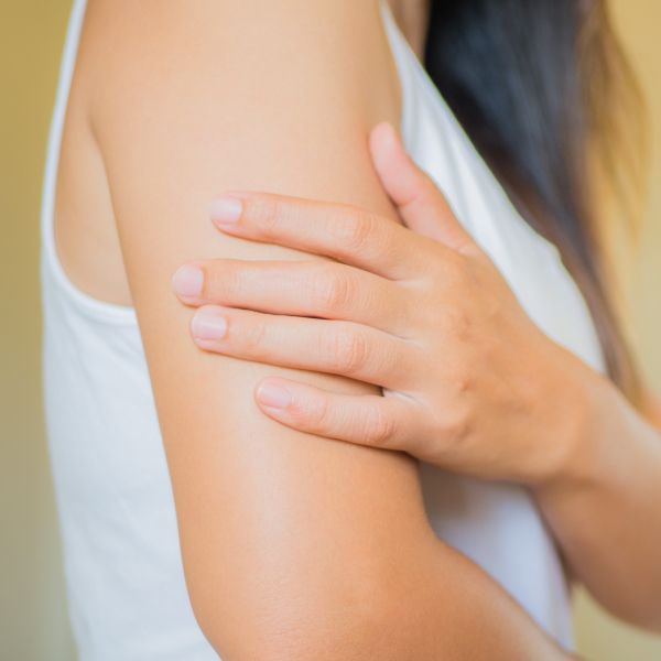 morpheus8 patient model in a white tank top touching her arm