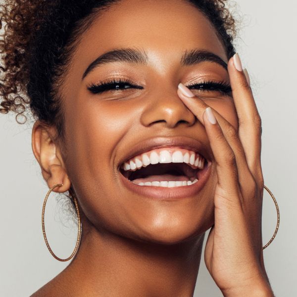 Smiling botox patient model with curly hair and earrings.