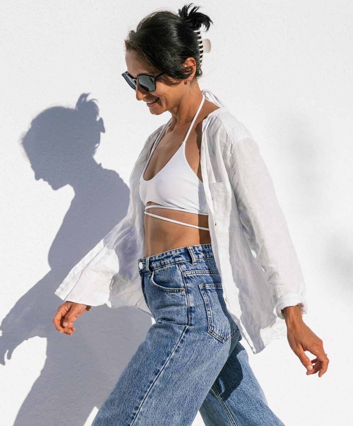 o shot patient model in stylish outfit walking against white wall.