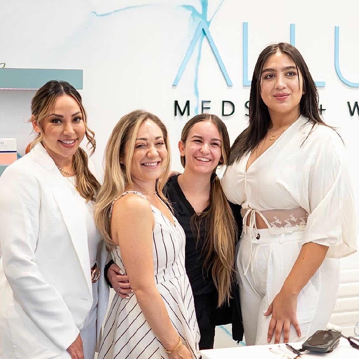 Group of four women smiling together indoors.