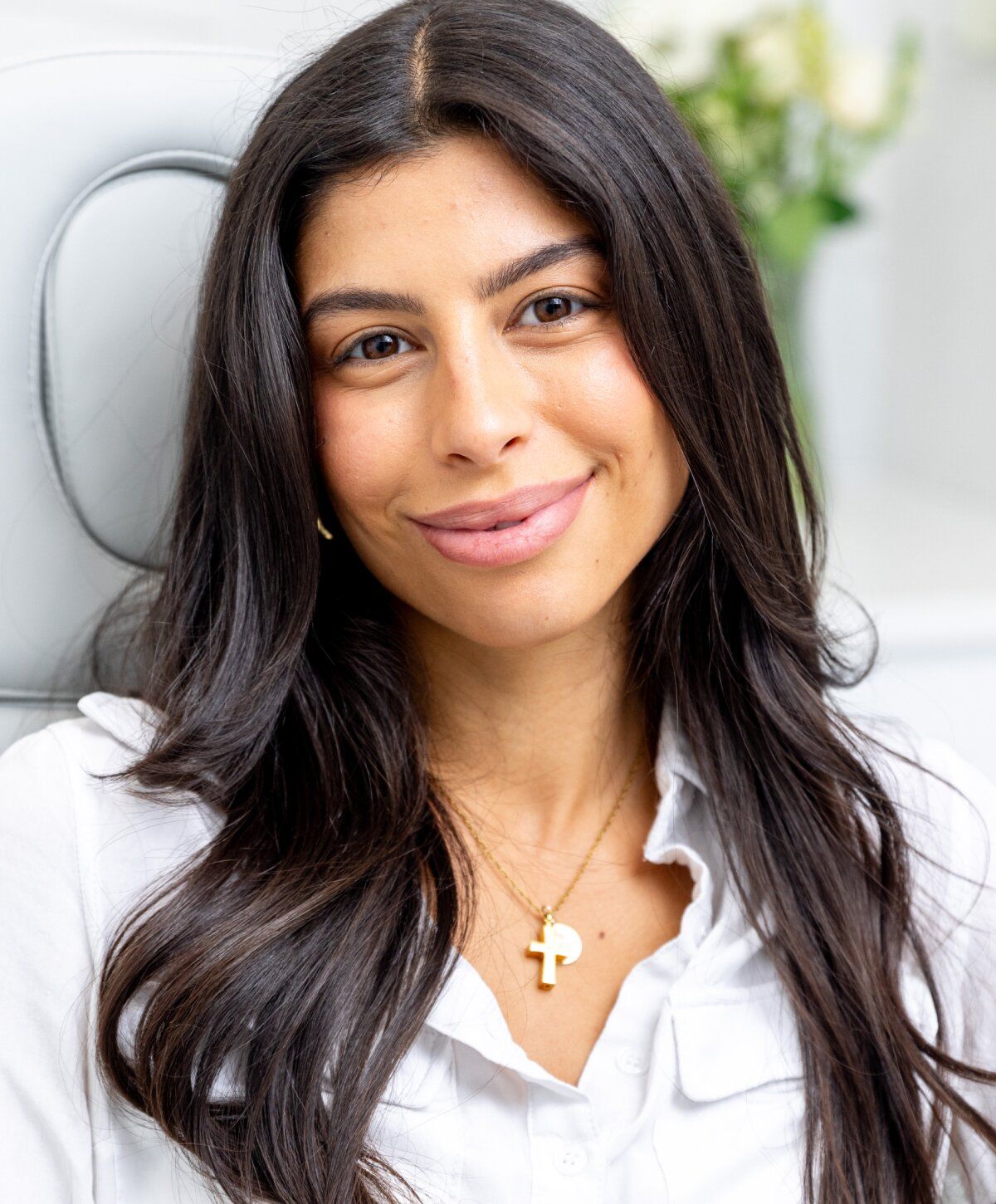 Smiling upneeq patient model with long dark hair and necklace.
