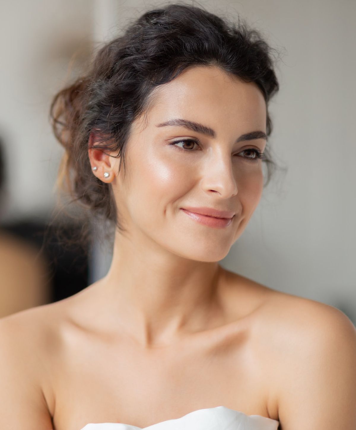 Smiling woman with curly hair and natural makeup.