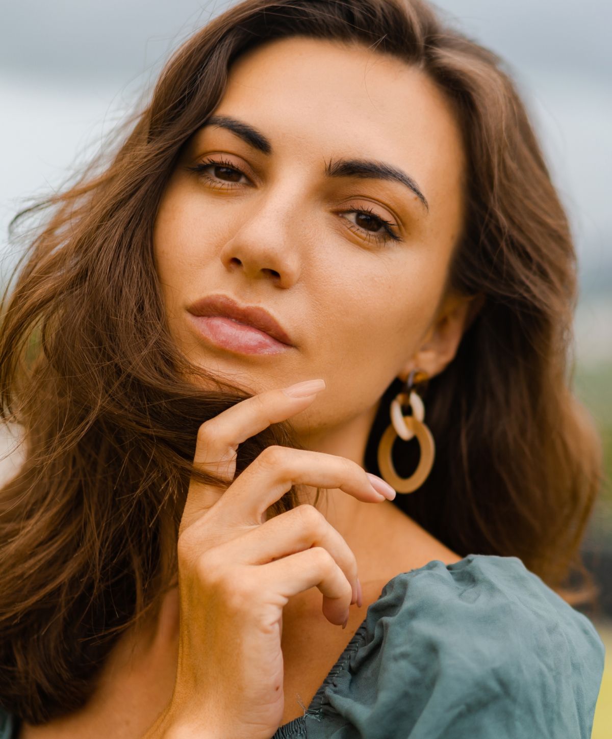 female jeuveau patient model with a blue dress touching her hair