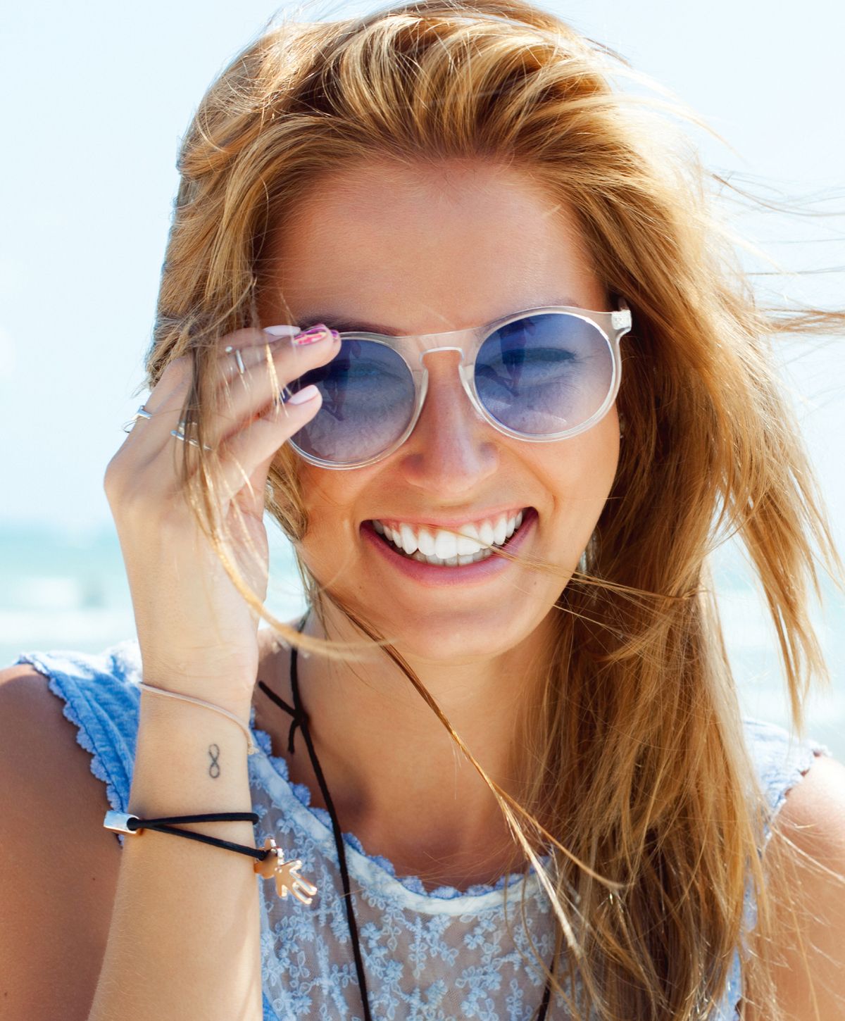 Smiling woman with curly hair enjoying sunlight.