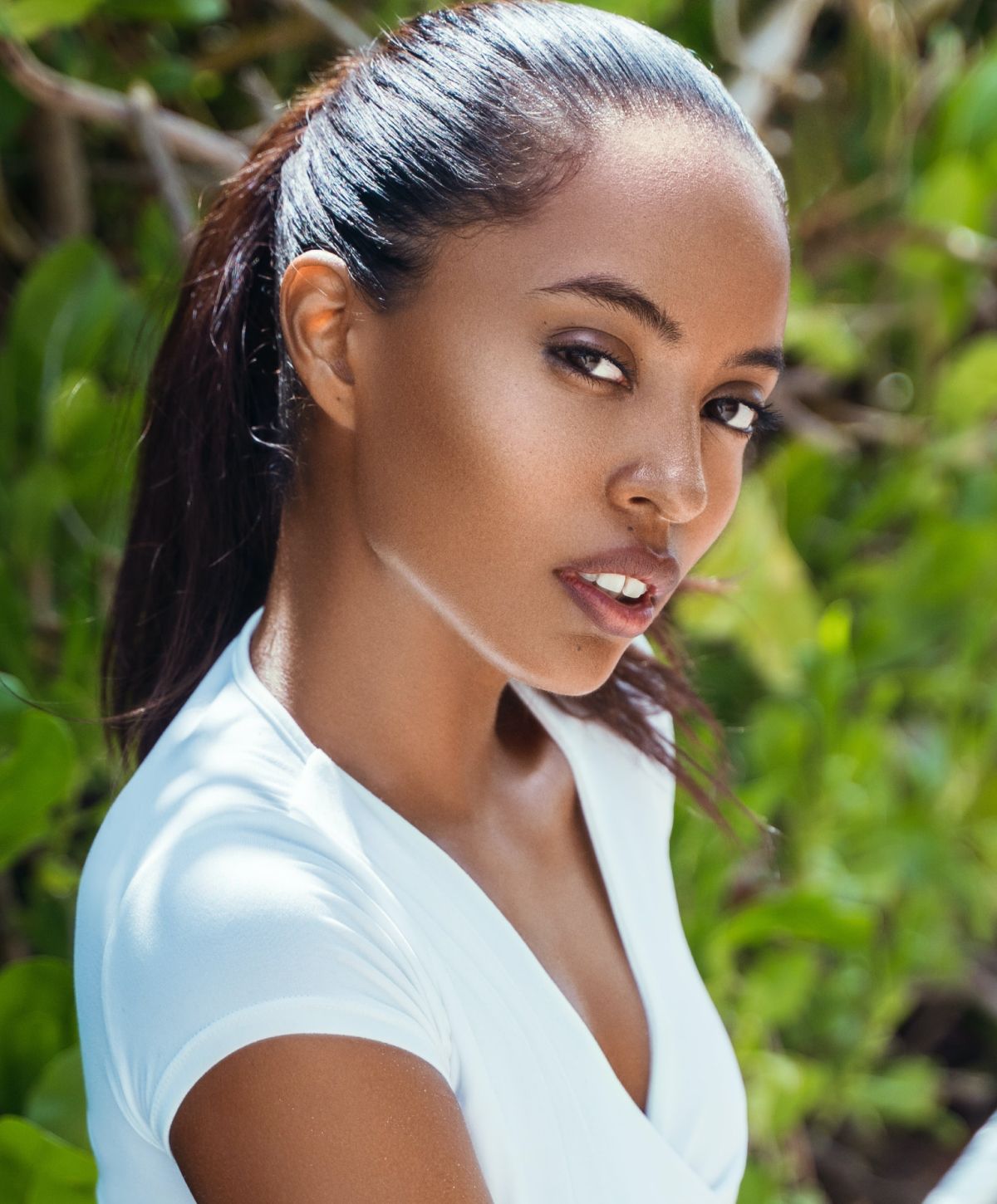 laser skin resurfacing model in a white shirt against a background of branches and leaves
