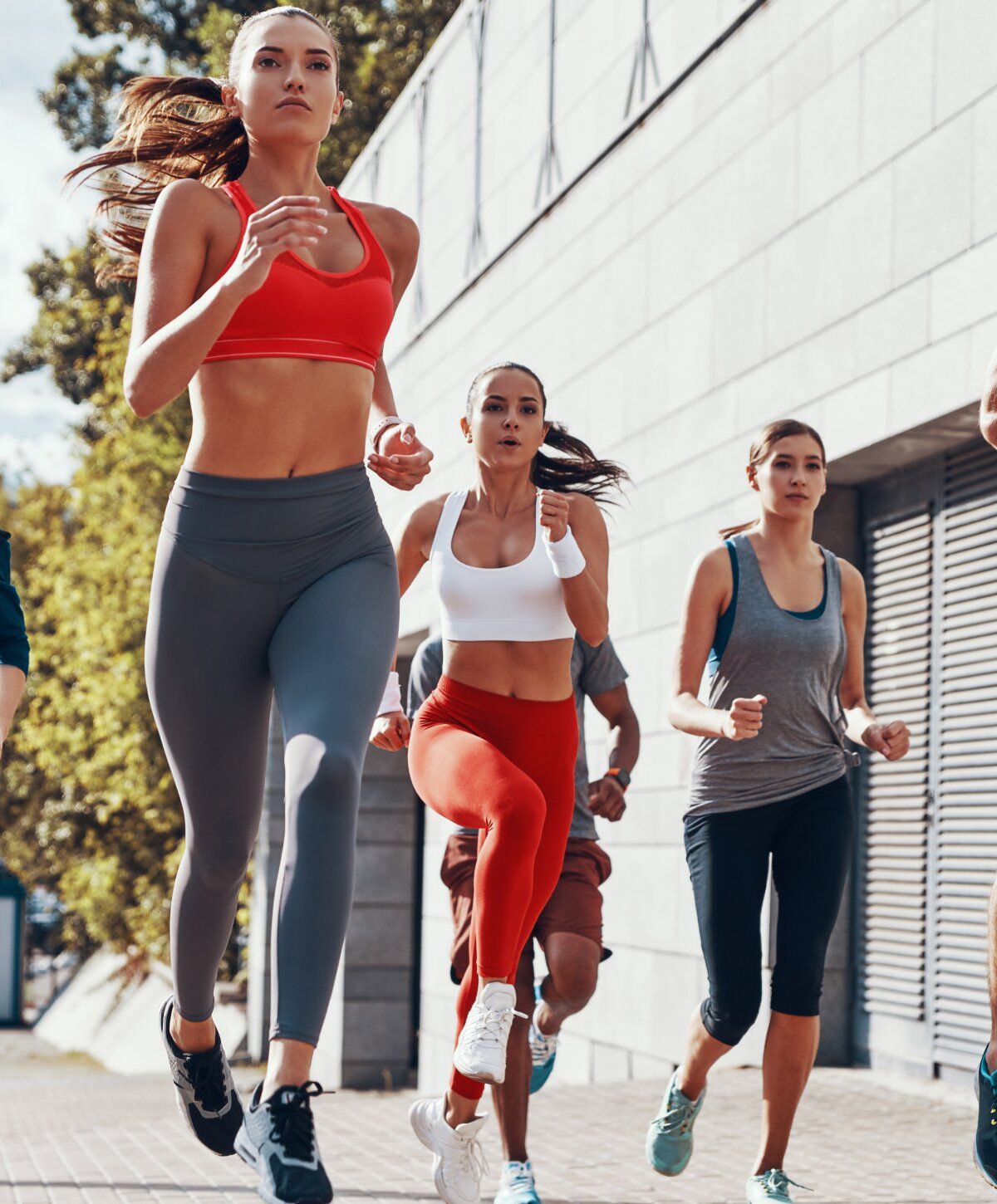 Group of people running outdoors in athletic wear.