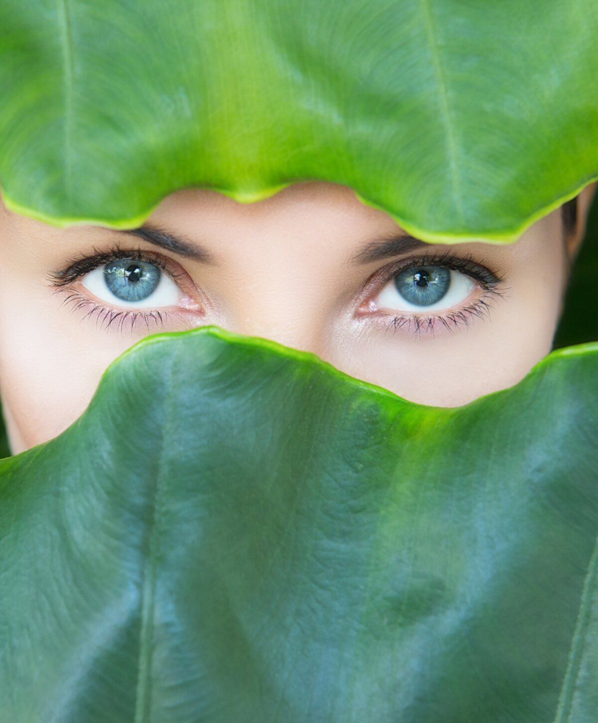 vitamin c iv therapy patient model peeking through lush green leaves.
