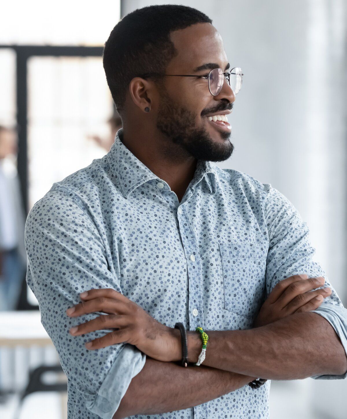 Smiling p shot patient model with glasses, arms crossed, casual attire.