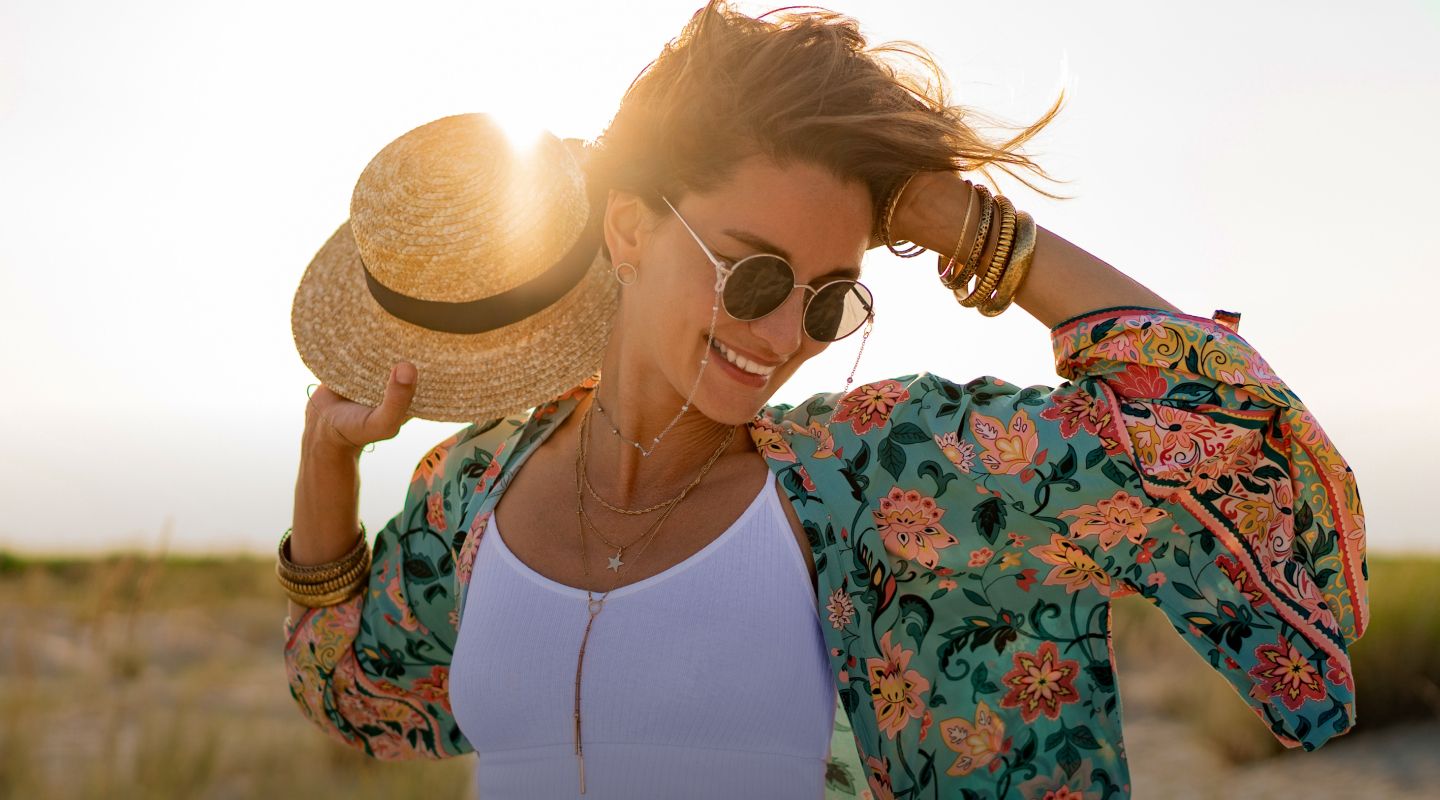 Woman enjoying sunlight, wearing sunglasses and hat.