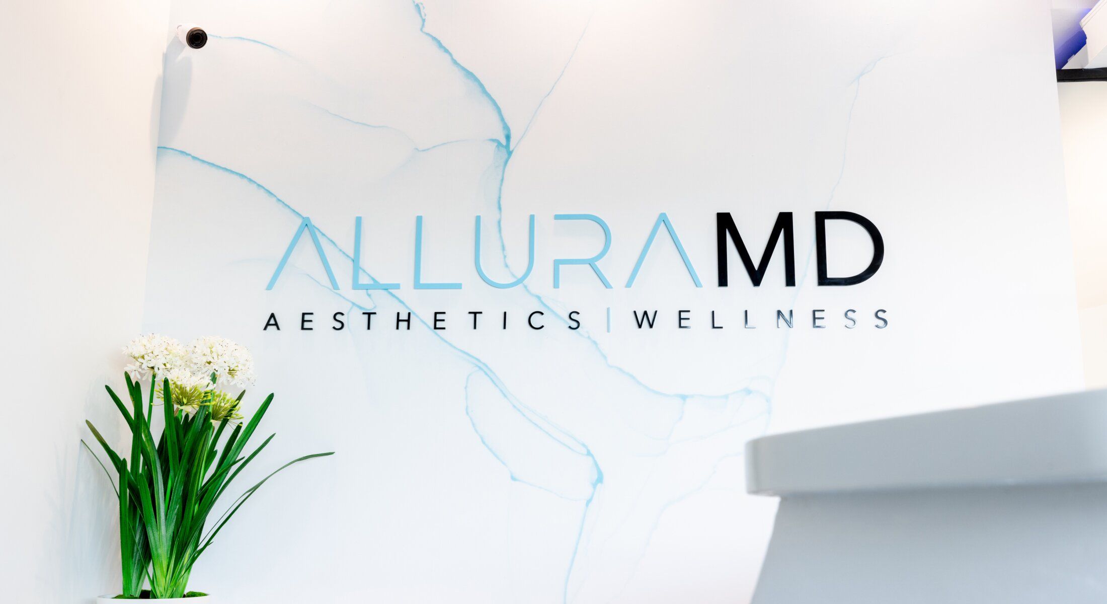 alluramd med spa reception area with logo on the wall