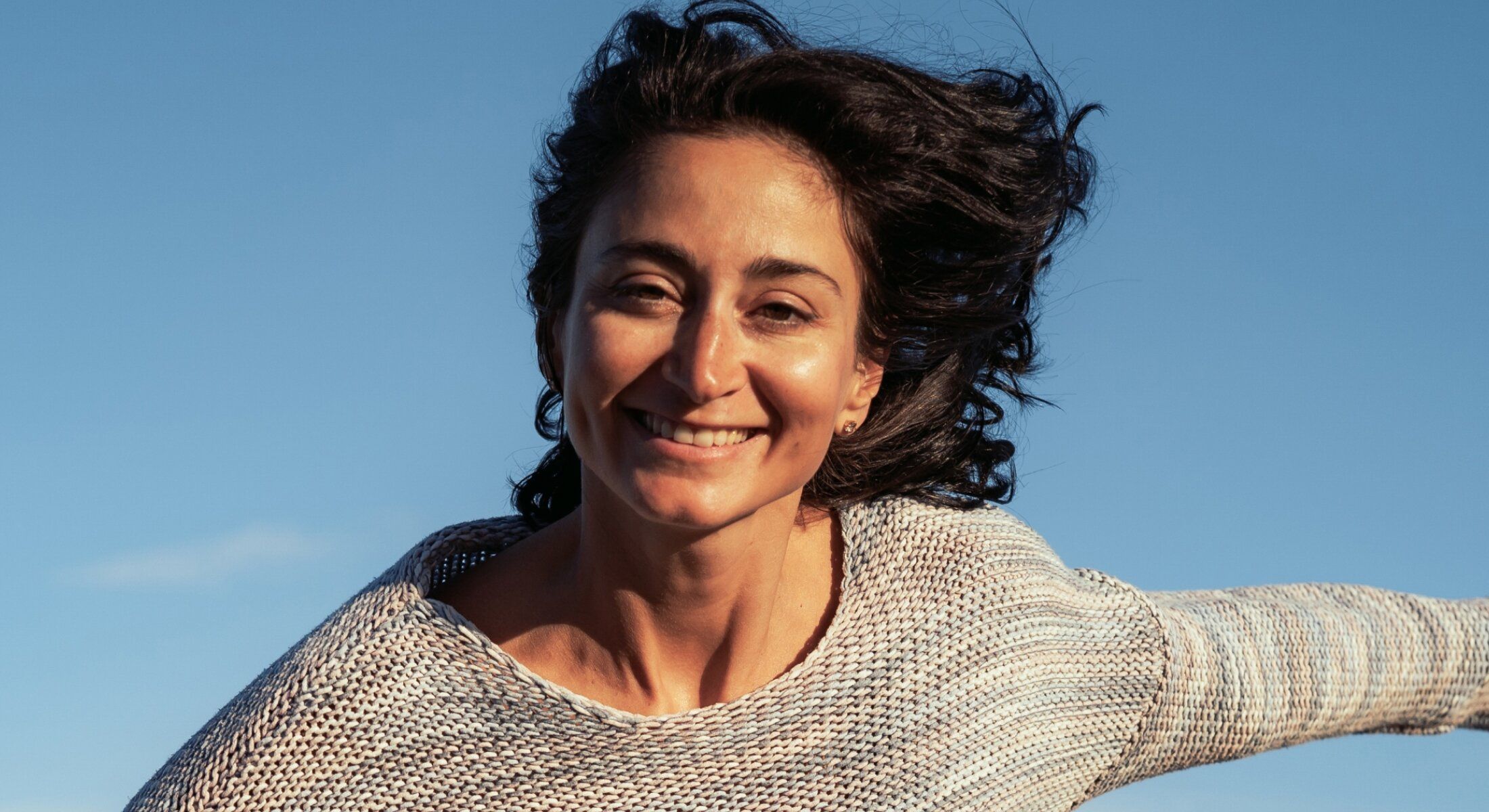 skin treatment patient model smiling against a blue sky background.
