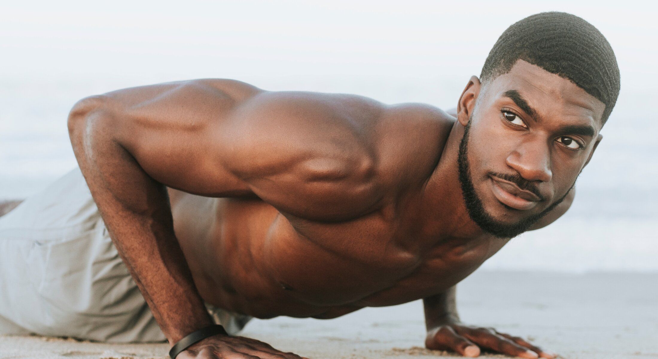 medical services patient model doing push-ups on the beach.