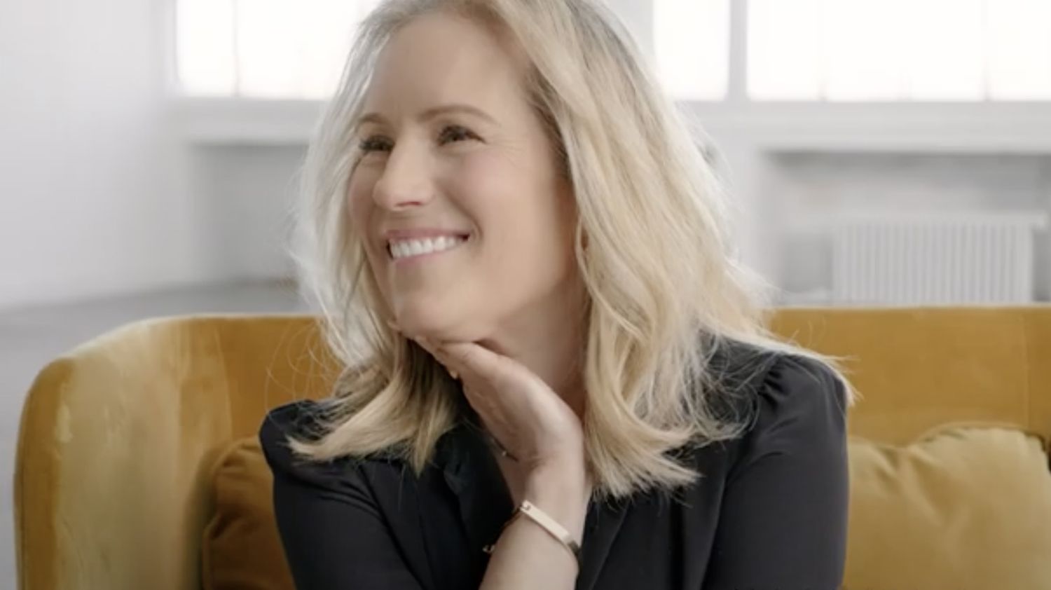Smiling woman sitting on a sofa, thoughtful pose.