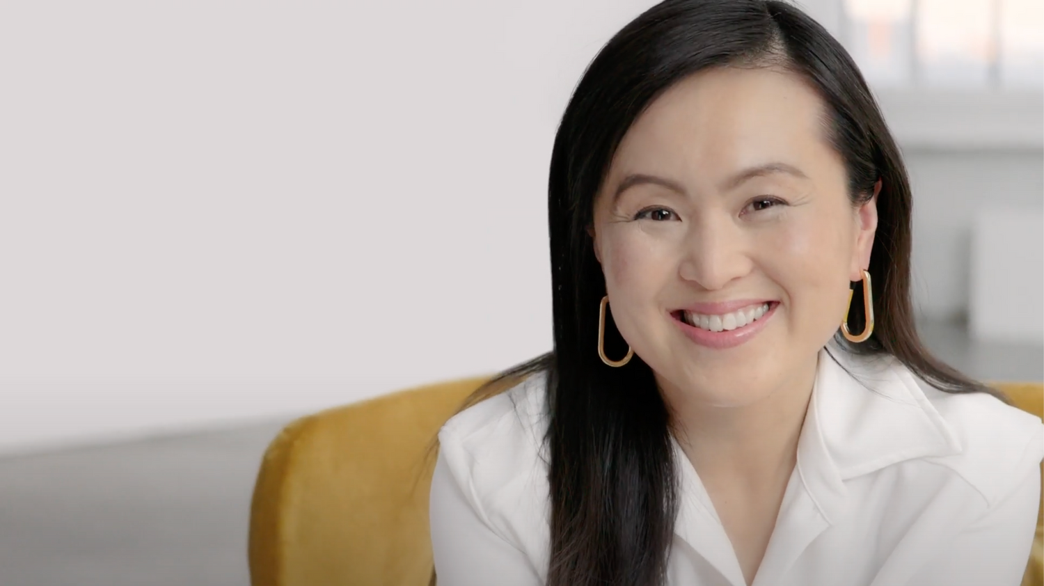 Smiling woman wearing earrings and white shirt.