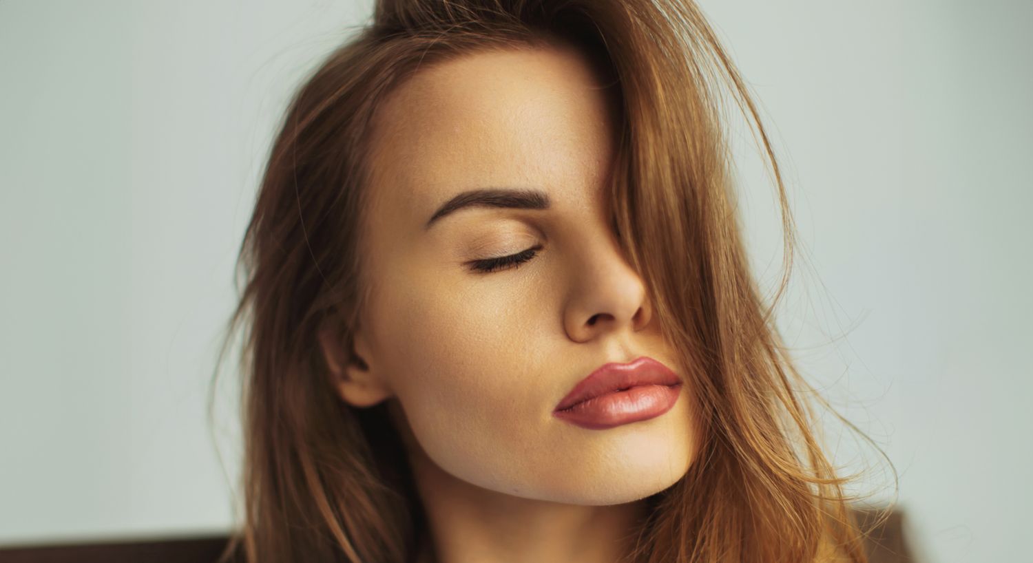 Facial Contouring patient model with red hair with her eyes closed wearing lipstick