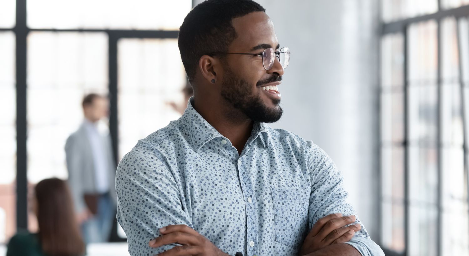 Growth Factor patient model in a patterned button up with his arms crossed