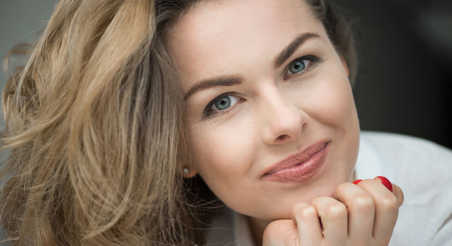 Ipamorelin patient model smiling and resting her chin in her palm