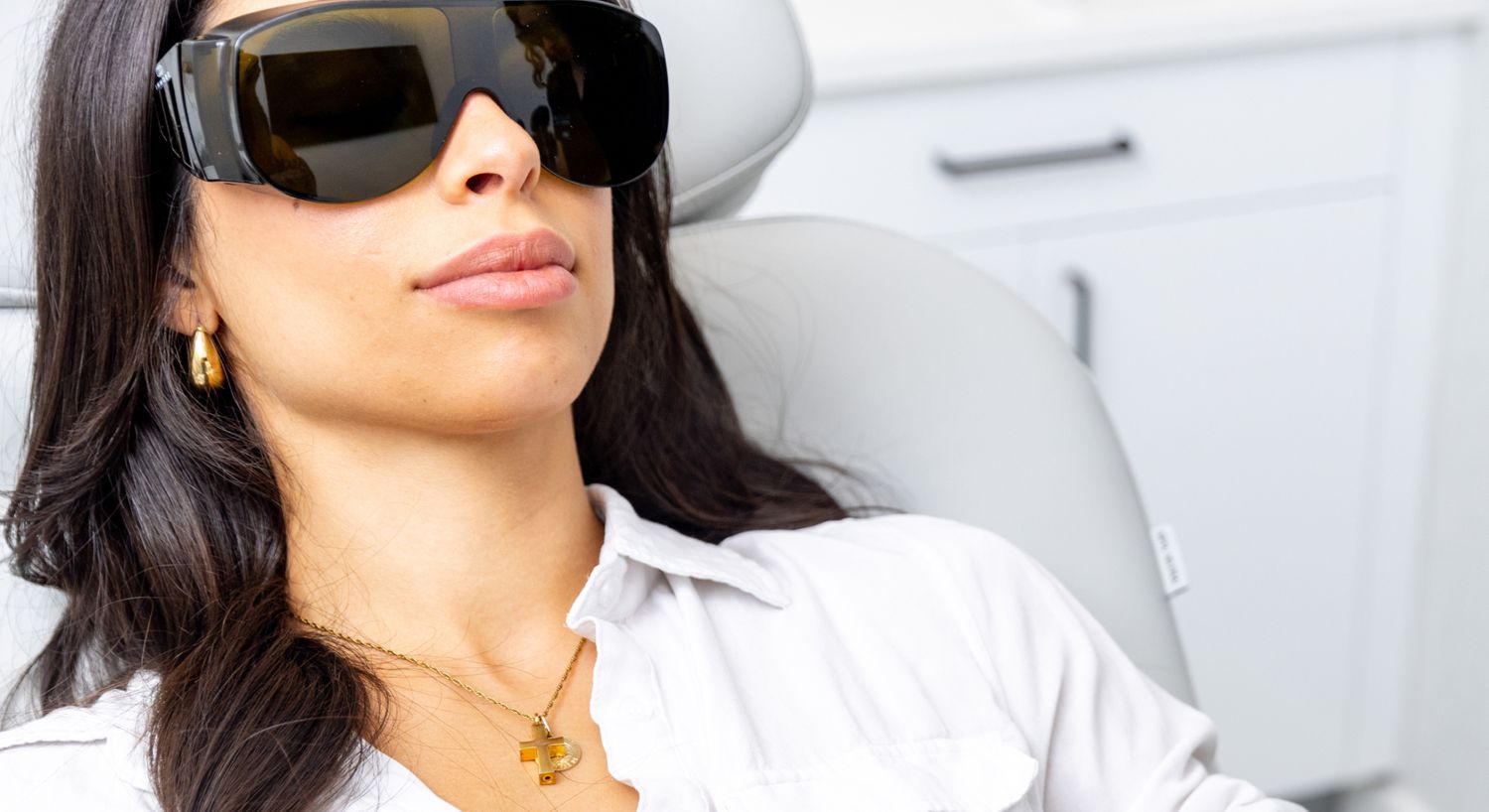 IPL Photofacial patient model sitting in a med spa chair with safety glasses on
