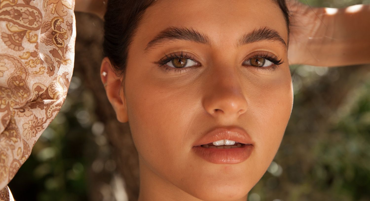 Upneeq Eyelid Lift patient model in a sun hat and floral dress