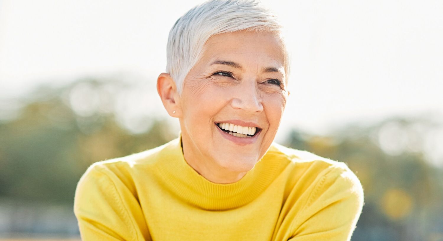 Chemical Peel patient model smiling outside wearing a yellow sweater